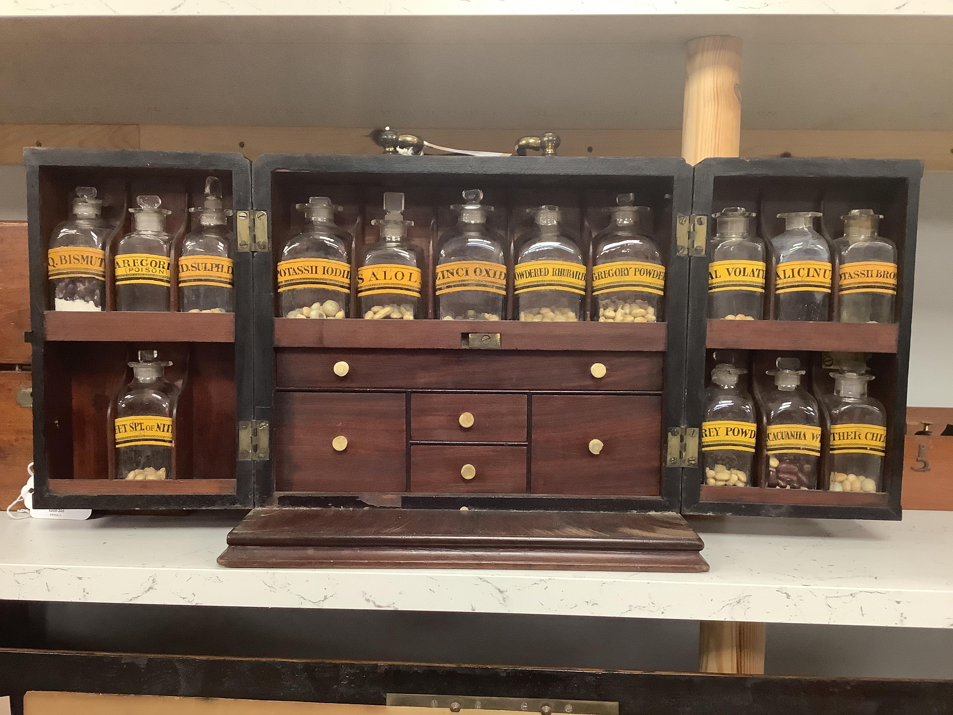 A Georgian mahogany domestic medicine chest, with bone drawer knobs and escutcheons, containing a number of glass square section drug bottles, fitted drawers containing scales, a pestle and mortar, etc., 29cm wide, 25cm